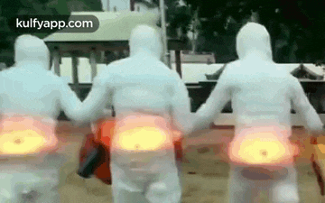 a group of people in white suits are walking down a street .