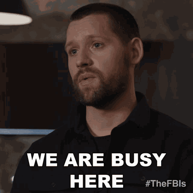 a man with a beard says " we are busy here " in a black shirt