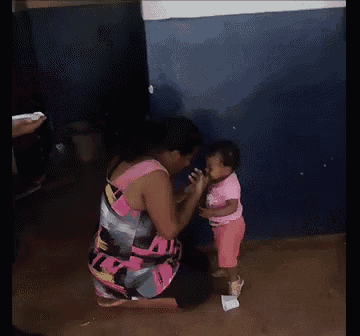 a woman in a pink dress is kneeling down next to a little girl .