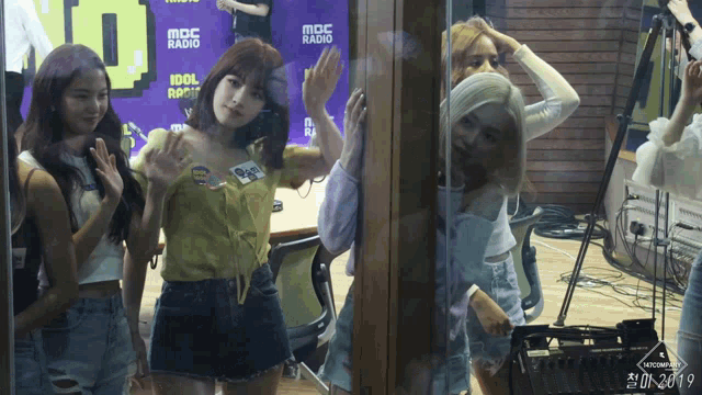 a group of women are standing in front of a mbc radio sign