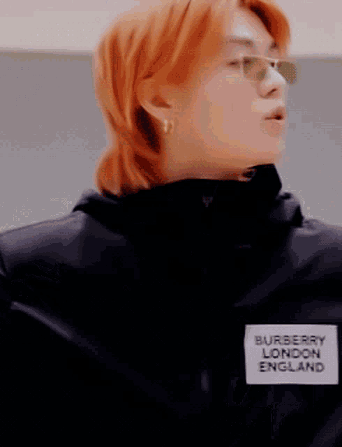 a close up of a person wearing sunglasses and a black jacket that says burberry london england