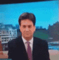 a man in a suit and tie is standing in front of a blue screen .