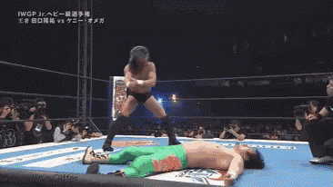 a wrestler in green pants is laying on the ground during a match