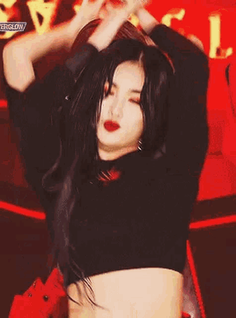 a woman with long black hair is wearing a black crop top and red lips .