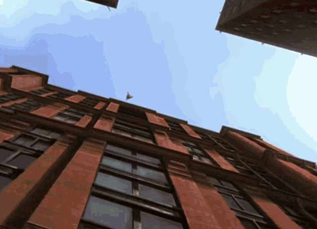 looking up at a tall brick building with a flag flying in the sky