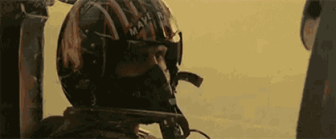a man wearing a helmet and a mask is sitting in a plane .
