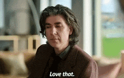 a man in a suit and tie is sitting in front of a window and says `` love that '' .