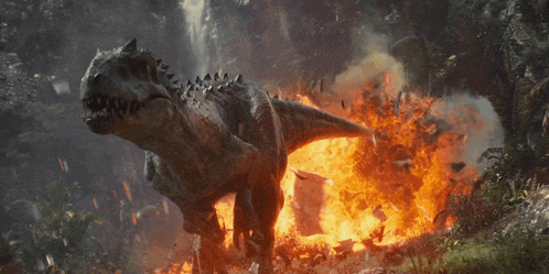 a dinosaur is surrounded by flames and smoke in a forest