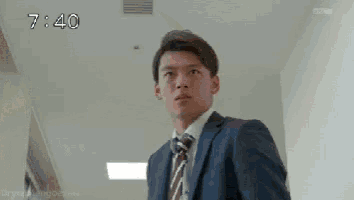 a man in a suit and tie is standing in a room .
