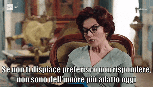 a woman wearing glasses sits in a chair with a caption that says " non sono dell ' amore piu adatto oggi "