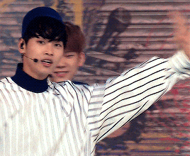 a man wearing a blue hat and a striped shirt stands next to another man