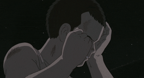 a man covering his face with his hand in a dark room