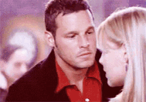 a man in a red shirt is kissing a woman in a black jacket .