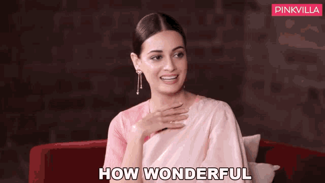 a woman in a pink saree is sitting on a red couch saying how wonderful