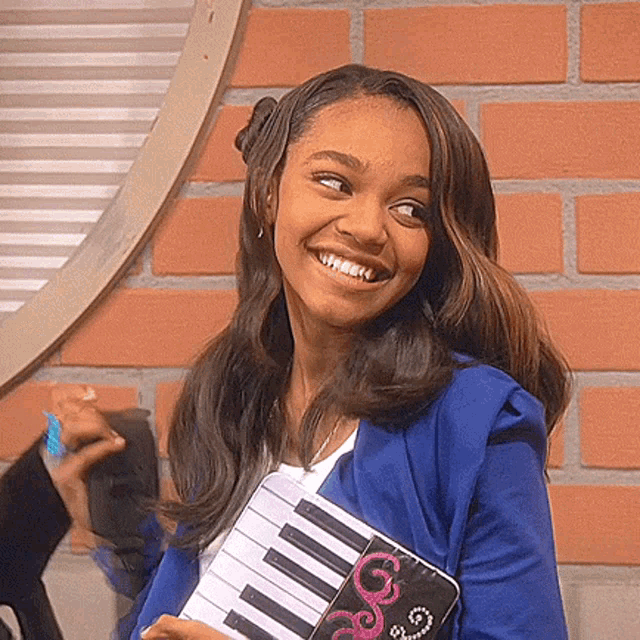 a woman in a blue jacket is smiling while holding a small piano keyboard .
