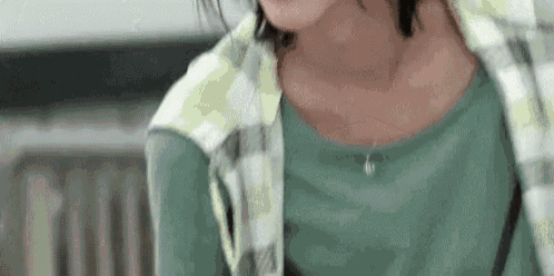 a close up of a woman wearing a green shirt and a plaid shirt .