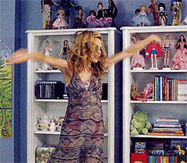 a woman is dancing in front of a shelf full of dolls and books