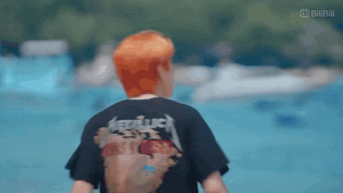 a man with red hair is wearing a black metallica shirt .