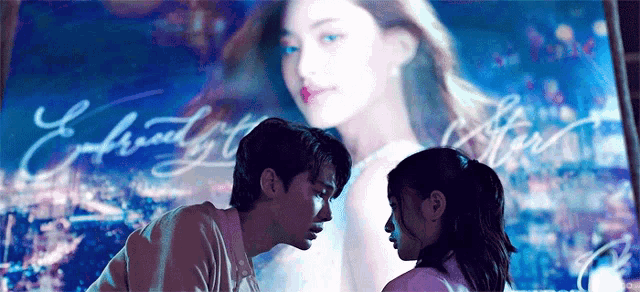 a man and a woman are looking at each other in front of a large screen with a picture of a woman on it .