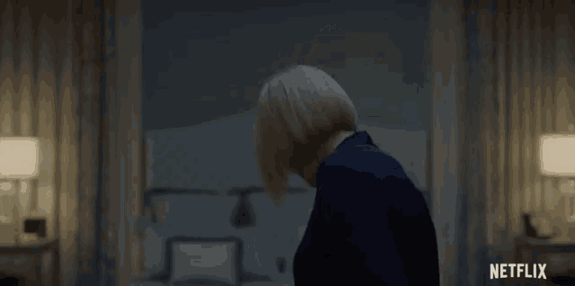 a woman is standing in front of a bed in a dark room with a netflix logo in the corner .
