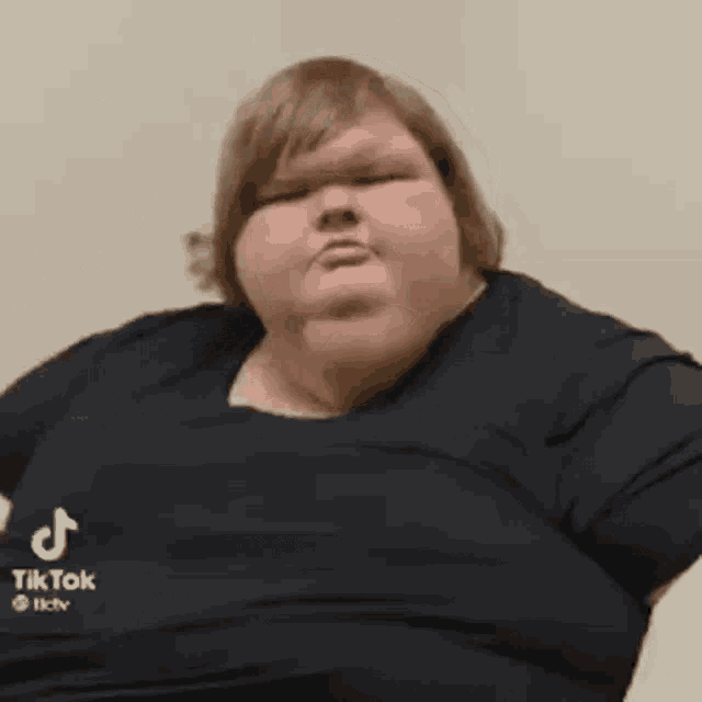 a very fat woman in a black shirt is sitting down .