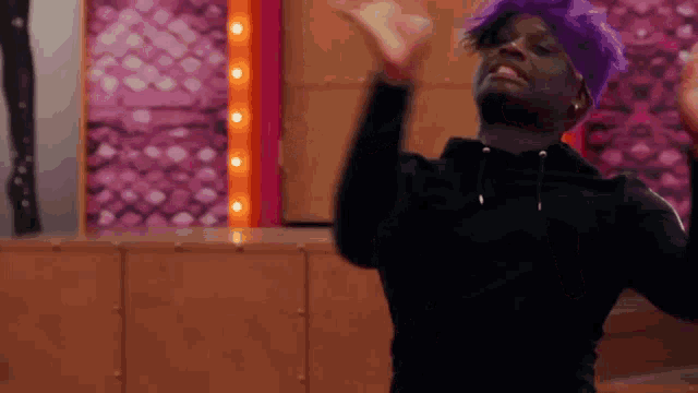 a man wearing a purple wig and a black hoodie is dancing .