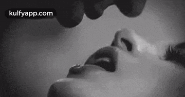 a black and white photo of a man kissing a woman on the lips .
