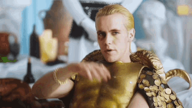 a man with gold paint on his face is wearing a gold armor with coins on it