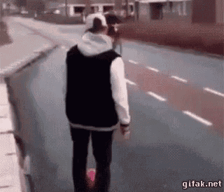a person is walking down a street with a skateboard .
