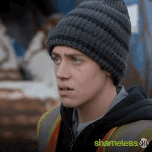 a man wearing a beanie and a safety vest with shameless show written on it