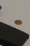 a penny is floating in the air on a table next to a black mat .