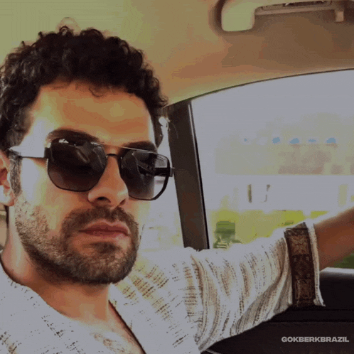 a man wearing sunglasses is sitting in a car with gokberkbrazil written on the bottom