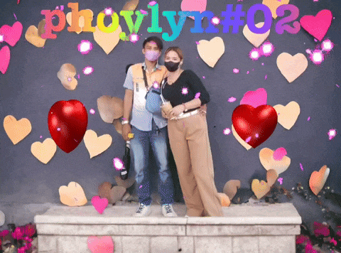a man and a woman are standing in front of a wall that says pholym # 02