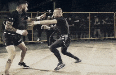two men are fighting in a boxing ring and one has a tattoo on his arm