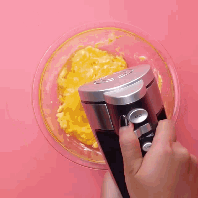 a person is using a mixer to mix something in a glass bowl