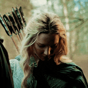 a woman is holding a bow and arrow in a forest