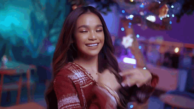 a woman in a plaid shirt is dancing in front of a christmas tree .