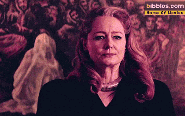 a woman stands in front of a painting that says bibblos.com on the bottom