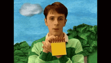 a man in a green and blue striped shirt holds a yellow notebook
