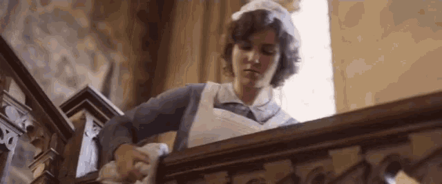 a woman in a nurse 's uniform is cleaning the railing of a staircase .