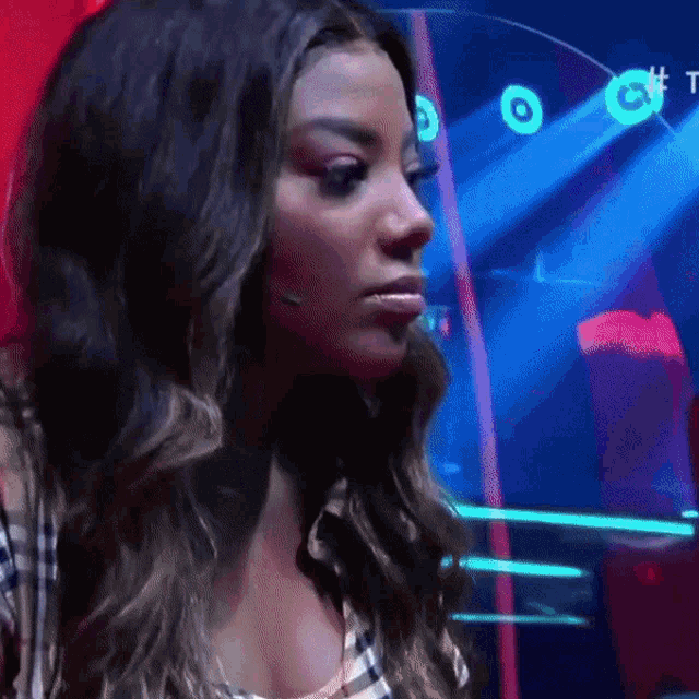 a woman in a plaid shirt is standing in front of a blue light with the letter t on it