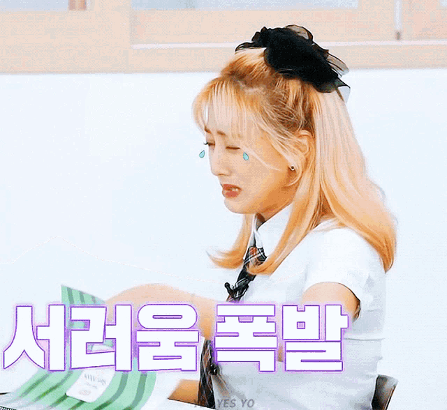 a girl with tears in her eyes is holding a piece of paper with korean writing
