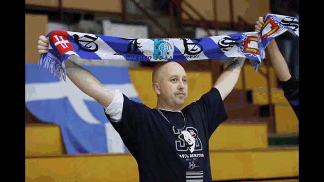 a man holds up a scarf that says ' s.f.e. ' on it