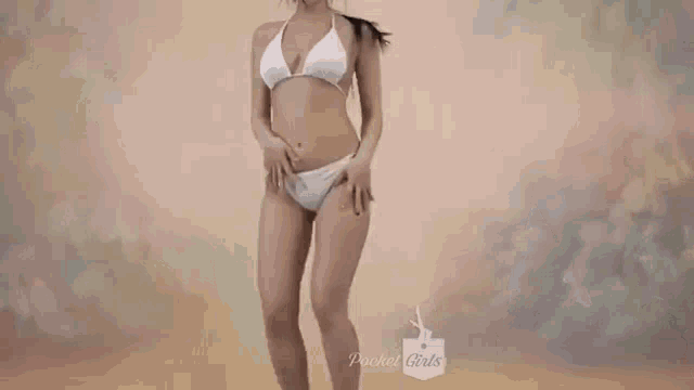 a woman in a white bikini is smiling while standing in front of a wall .