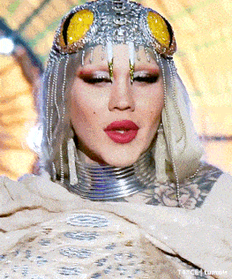 a close up of a woman 's face wearing a headpiece and a necklace