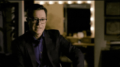 a man in a suit and glasses is making a face