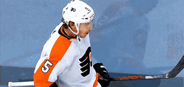 a hockey player with the number 5 on his jersey holds a hockey stick