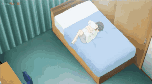a boy is laying on a bed with a blue blanket and a white pillow