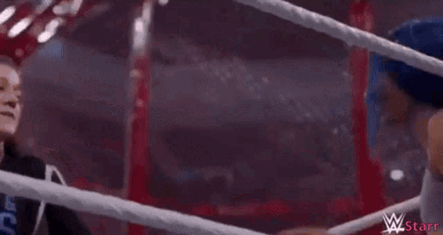 two women are hugging in a wrestling ring .