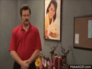 a man in a red shirt is standing in front of a framed picture of a woman .